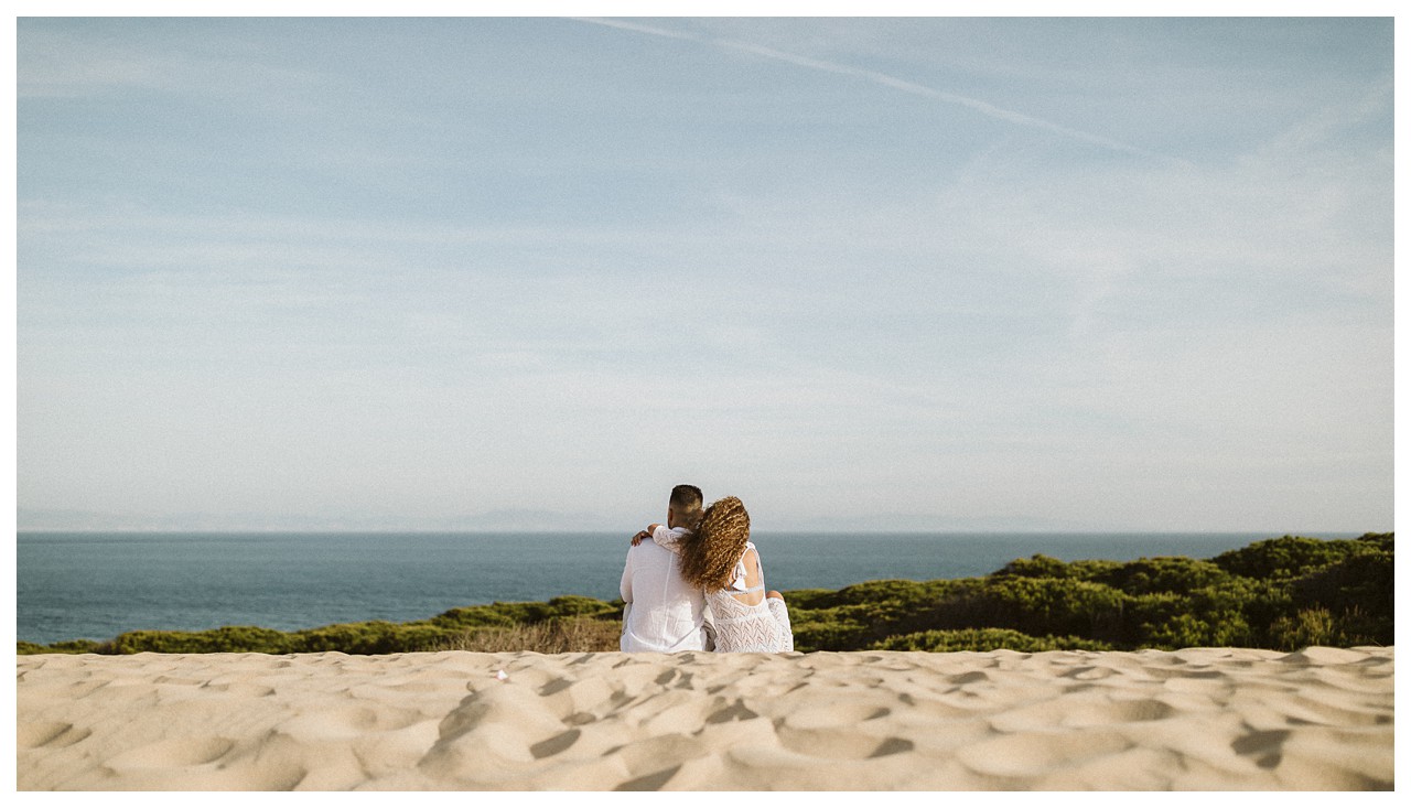 Una pareja mirando el horizonte en la playa